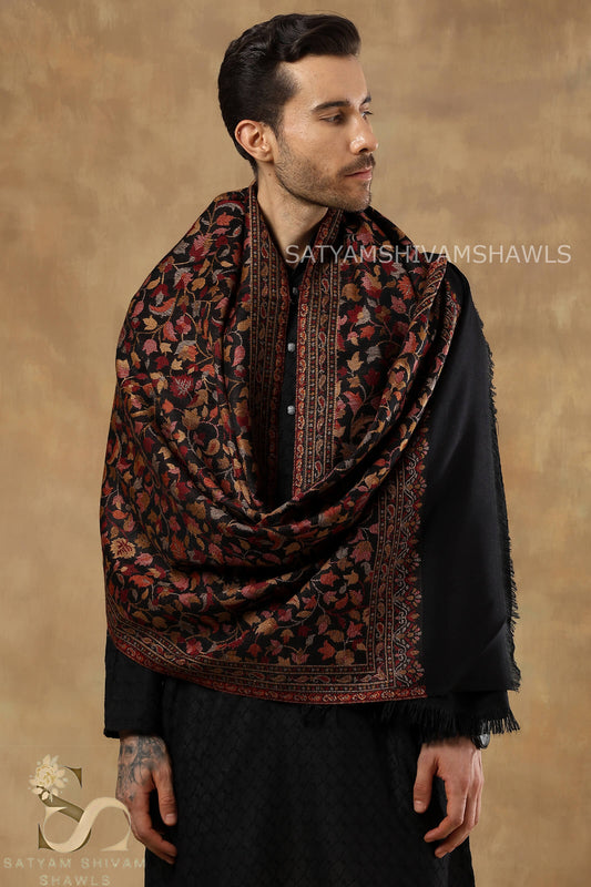 Man wearing a patterned shawl with 'Satyamshwam Shawls' branding on a beige background